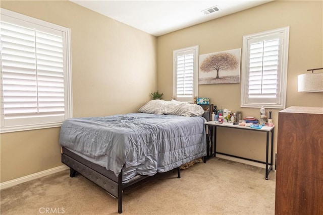 bedroom with light colored carpet and multiple windows