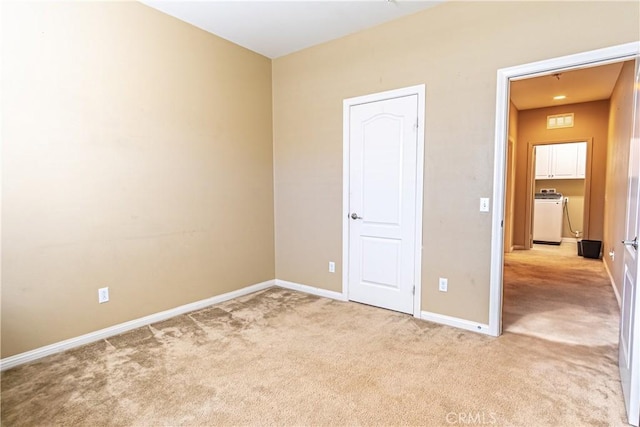 unfurnished bedroom with light colored carpet and washer / dryer