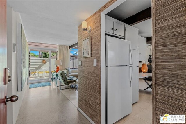 kitchen featuring wood walls, white refrigerator, and white cabinets