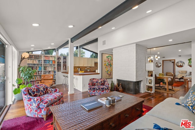 living room featuring hardwood / wood-style flooring, a brick fireplace, and vaulted ceiling with beams