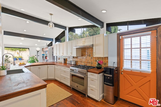 kitchen with vaulted ceiling with beams, stainless steel stove, sink, white cabinetry, and decorative light fixtures