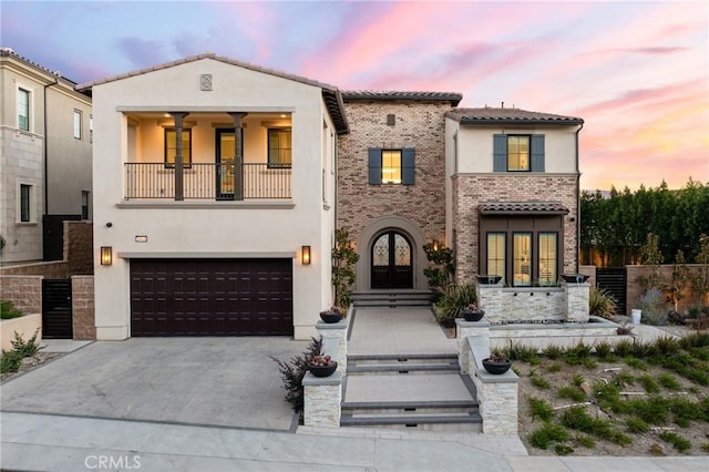 mediterranean / spanish-style house with a garage, french doors, and a balcony