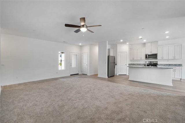 unfurnished living room featuring ceiling fan and light hardwood / wood-style floors