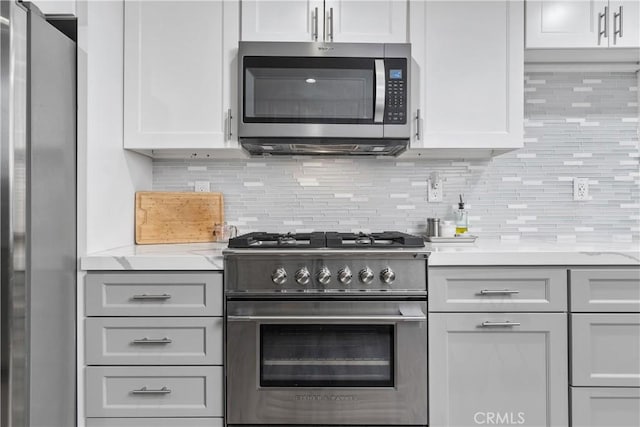 kitchen with light stone counters, appliances with stainless steel finishes, gray cabinets, and tasteful backsplash