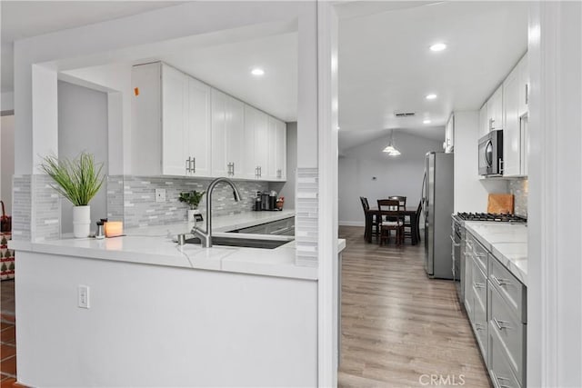 kitchen with backsplash, appliances with stainless steel finishes, sink, and white cabinetry