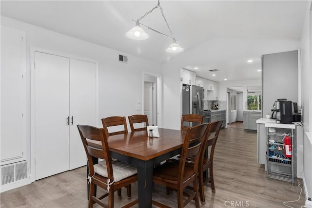 dining area featuring lofted ceiling and light hardwood / wood-style flooring