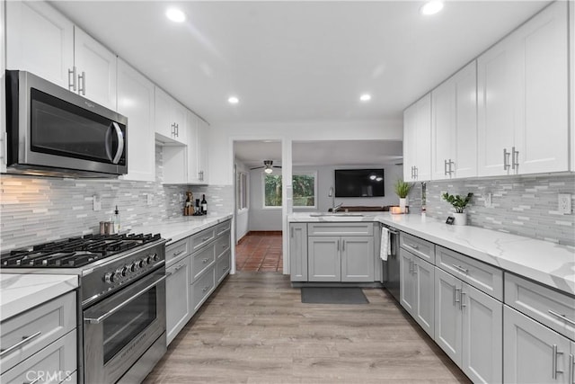 kitchen featuring stainless steel appliances, decorative backsplash, white cabinets, and light stone counters