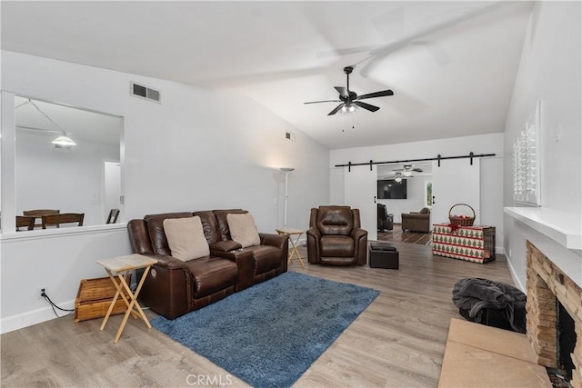 living room featuring lofted ceiling, a barn door, and hardwood / wood-style floors