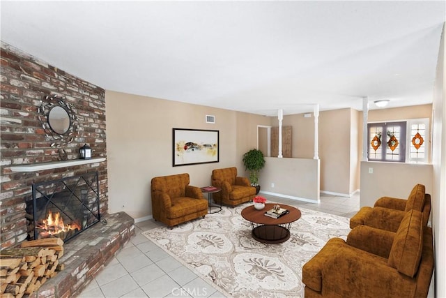 tiled living room featuring a brick fireplace, visible vents, and baseboards