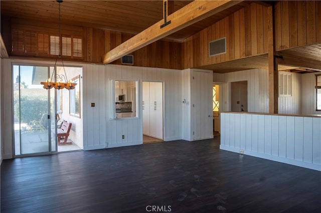 spare room with dark hardwood / wood-style floors, wooden walls, and an inviting chandelier