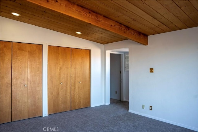 unfurnished bedroom with two closets, dark carpet, lofted ceiling with beams, and wood ceiling