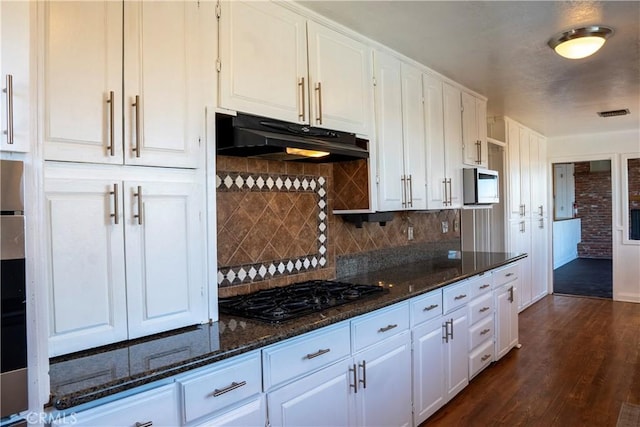 kitchen featuring white cabinetry, backsplash, dark hardwood / wood-style flooring, black gas stovetop, and dark stone counters