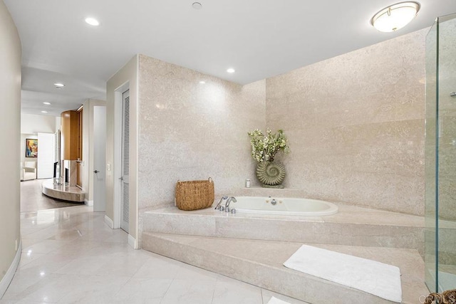 bathroom with tile walls and tiled tub