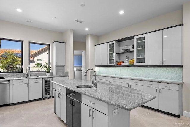 kitchen featuring light stone countertops, sink, a kitchen island with sink, and wine cooler