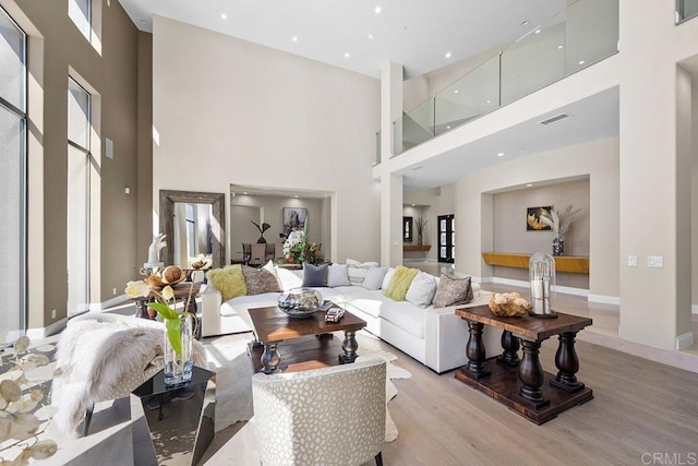 living room featuring a towering ceiling and light hardwood / wood-style floors