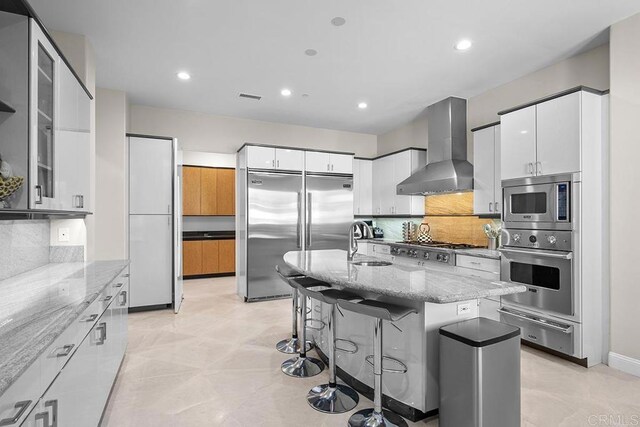 1107 Majestad Ln, Chula Vista, CA 91910 - kitchen featuring a warming drawer, wall chimney exhaust hood, light stone counters, and built in appliances