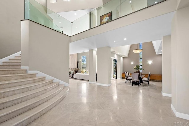 entrance foyer featuring a high ceiling, stairway, marble finish floor, baseboards, and plenty of natural light