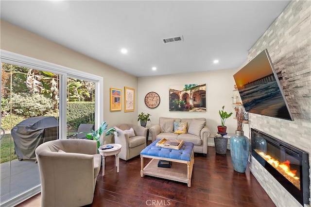 living room featuring dark wood-type flooring and a stone fireplace