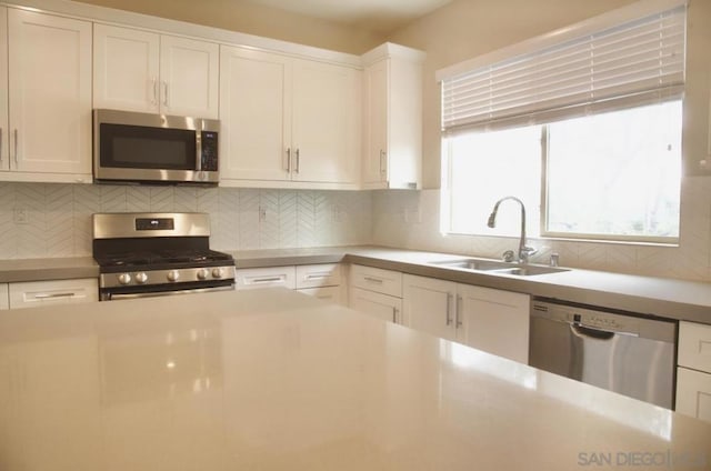 kitchen with white cabinets, backsplash, appliances with stainless steel finishes, and sink