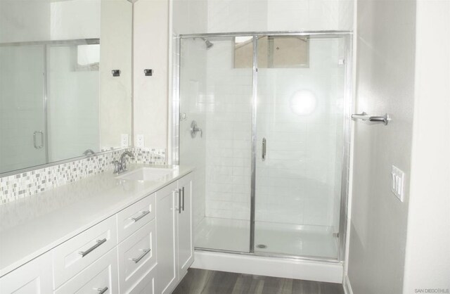 bathroom featuring tasteful backsplash, vanity, a shower with shower door, and hardwood / wood-style floors