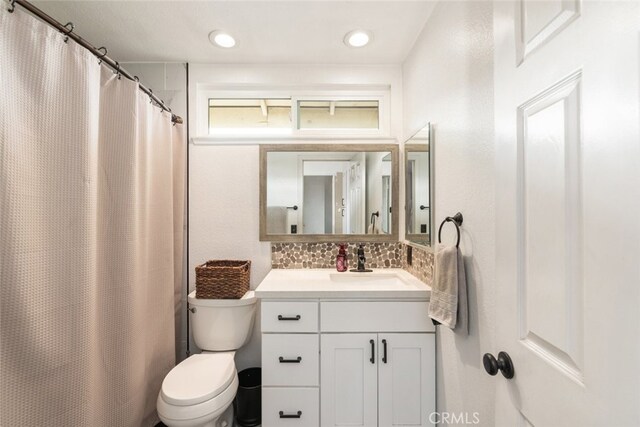 bathroom featuring toilet, vanity, and decorative backsplash