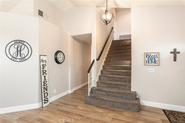 stairs with wood-type flooring and a notable chandelier