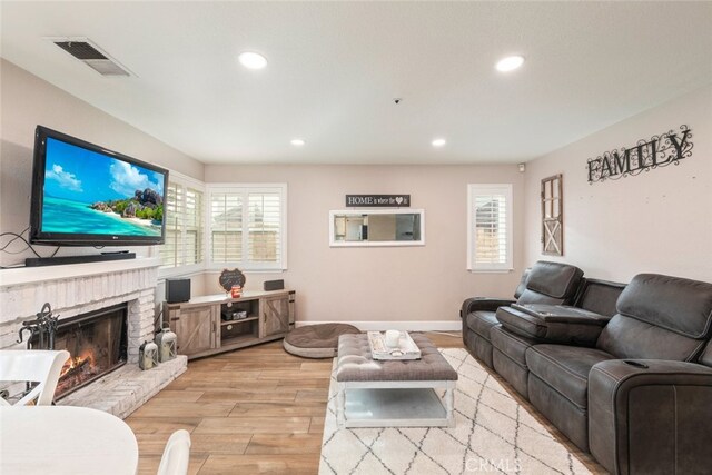 living room with a brick fireplace and light hardwood / wood-style flooring