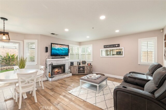 living room with light hardwood / wood-style flooring, a healthy amount of sunlight, and a fireplace