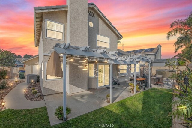 back house at dusk with a lawn, central air condition unit, a pergola, and a patio area