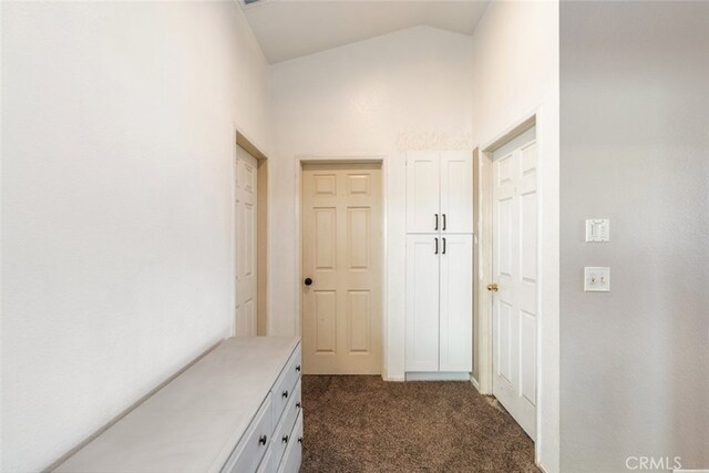 hall with vaulted ceiling and dark colored carpet