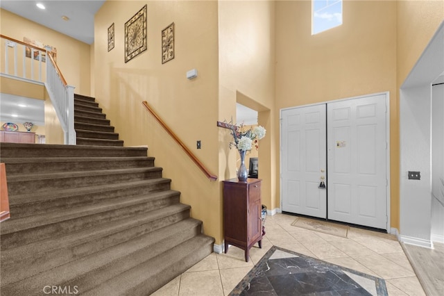 foyer entrance with light tile patterned flooring and a high ceiling