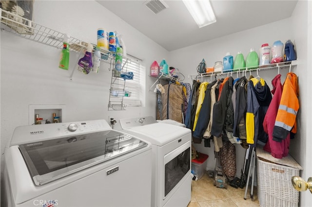 clothes washing area featuring washing machine and dryer and light tile patterned flooring