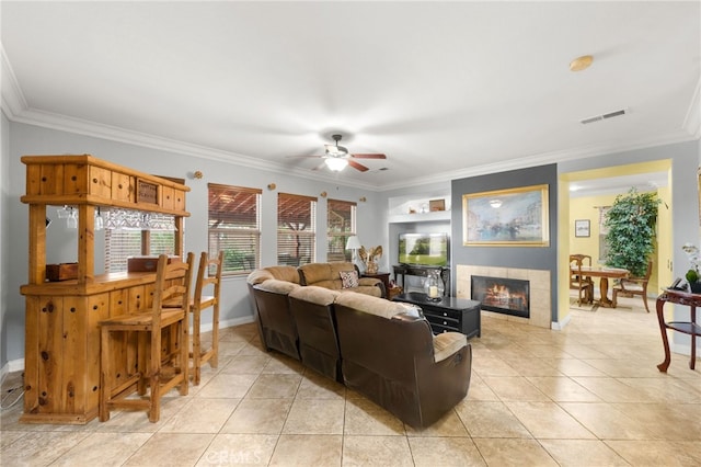 tiled living room with ceiling fan, built in features, a fireplace, and ornamental molding