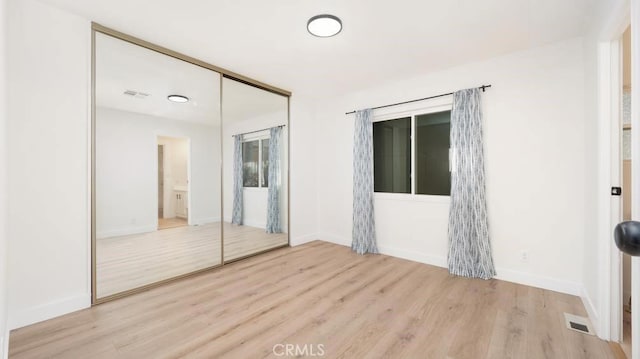 unfurnished bedroom with light wood-type flooring and a closet