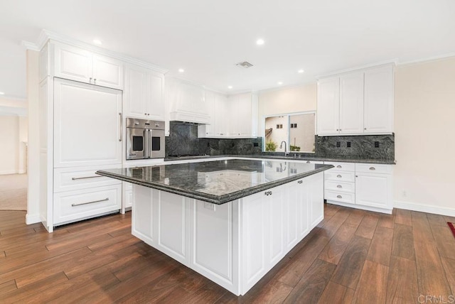 kitchen featuring sink, white cabinets, a center island, and stainless steel oven