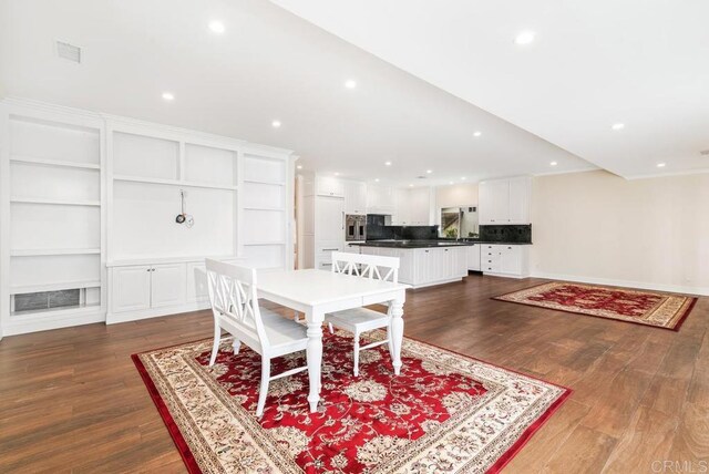 dining space featuring dark wood-type flooring and built in shelves