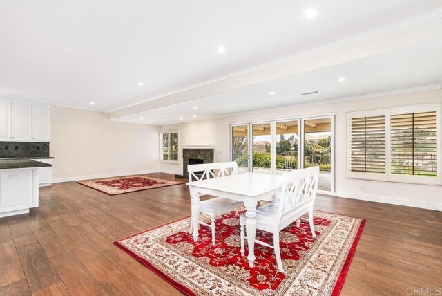 dining space featuring dark hardwood / wood-style floors, a high end fireplace, and crown molding