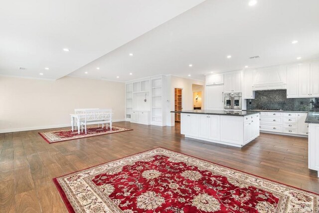 kitchen with a kitchen island, dark wood-type flooring, white cabinetry, premium range hood, and stainless steel oven