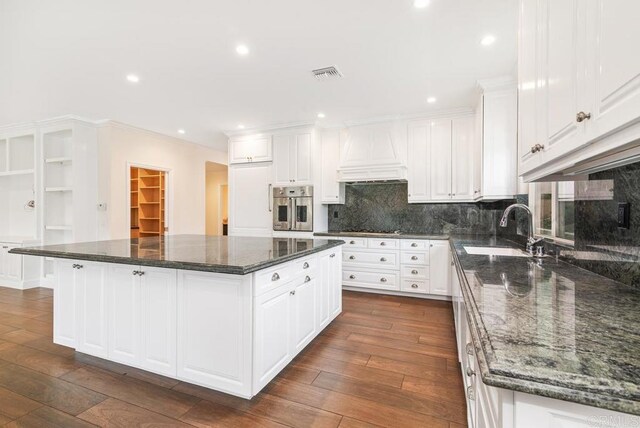 kitchen featuring oven, dark stone countertops, white cabinets, and a center island