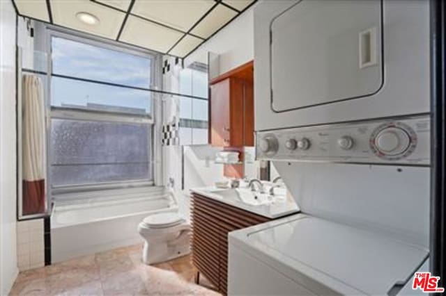 clothes washing area with light tile patterned floors and stacked washer and clothes dryer