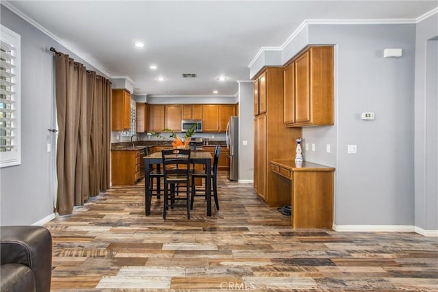 kitchen featuring sink, hardwood / wood-style floors, ornamental molding, and stainless steel appliances