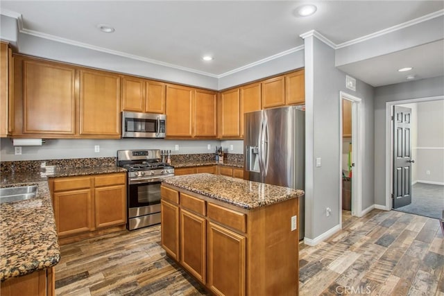 kitchen featuring dark hardwood / wood-style flooring, a center island, dark stone counters, and stainless steel appliances