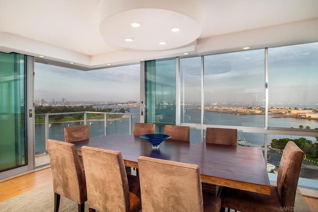 dining room featuring a water view, a wealth of natural light, floor to ceiling windows, and hardwood / wood-style floors