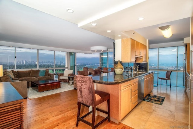 kitchen featuring sink, a breakfast bar area, dishwasher, light hardwood / wood-style floors, and backsplash