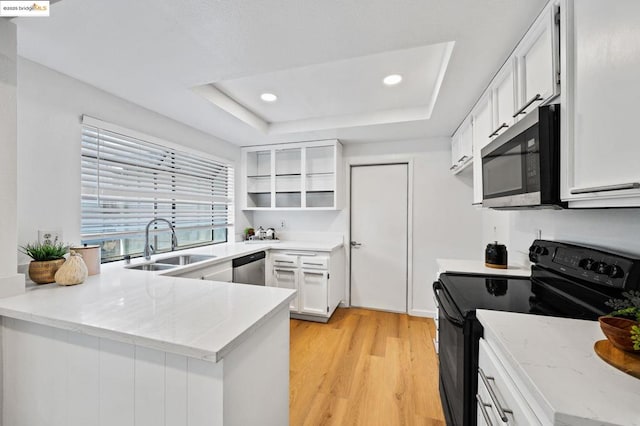 kitchen with appliances with stainless steel finishes, white cabinetry, sink, kitchen peninsula, and a raised ceiling