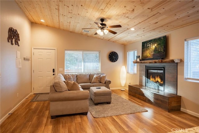 living room with ceiling fan, wood-type flooring, wood ceiling, and a tiled fireplace