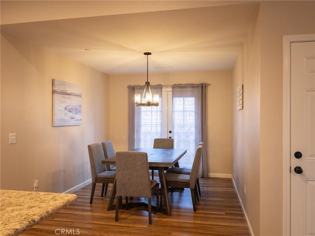 dining space with french doors, dark hardwood / wood-style flooring, and a notable chandelier