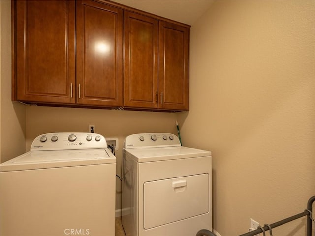 washroom with washer and dryer and cabinets