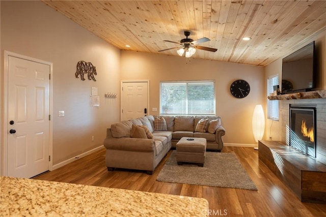 living room with ceiling fan, vaulted ceiling, a tile fireplace, wood-type flooring, and wood ceiling