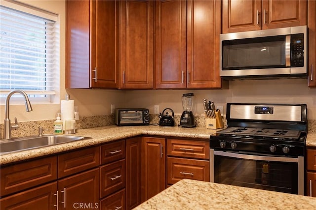 kitchen with light stone countertops, appliances with stainless steel finishes, and sink